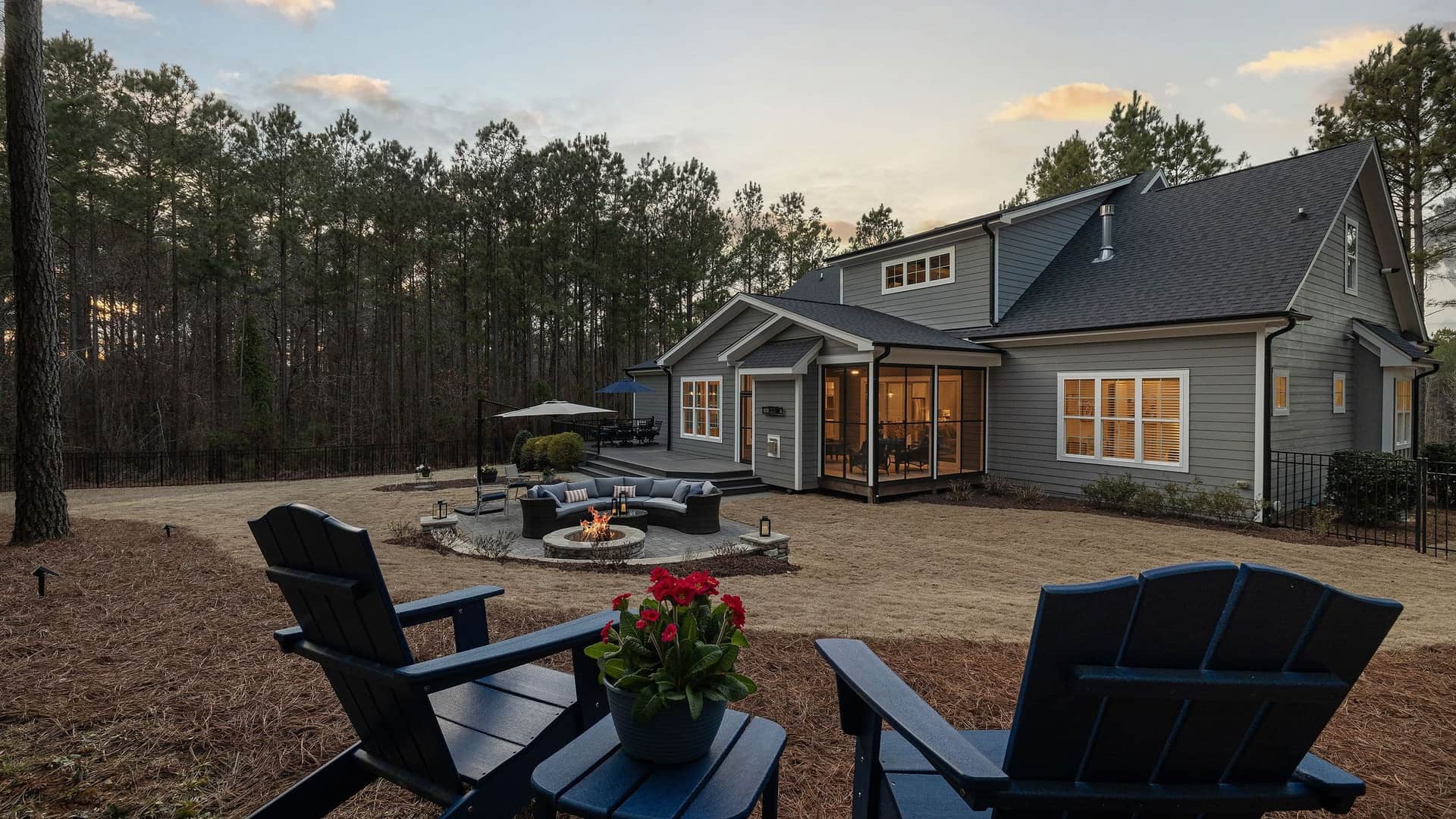 A finished concrete patio and fire pit behind a home at dusk