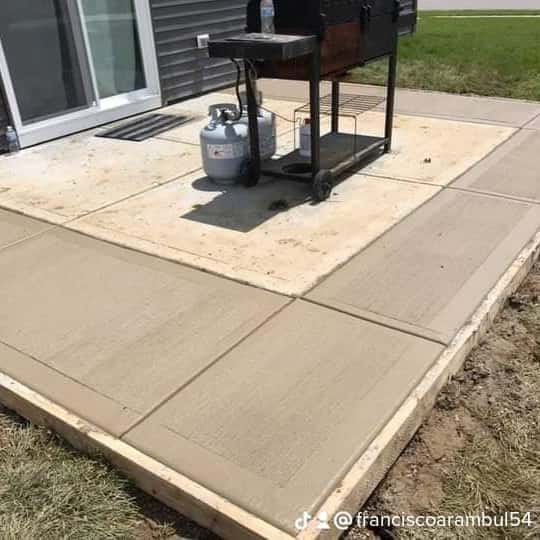 Freshly poured broom-finished backyard patio slab beside a grill, forms still in place — JFC Concrete LLC, Indianapolis, IN
