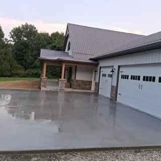 Wide new driveway leading to a home with a metal roof and three-car garage — JFC Concrete LLC, Indianapolis, IN